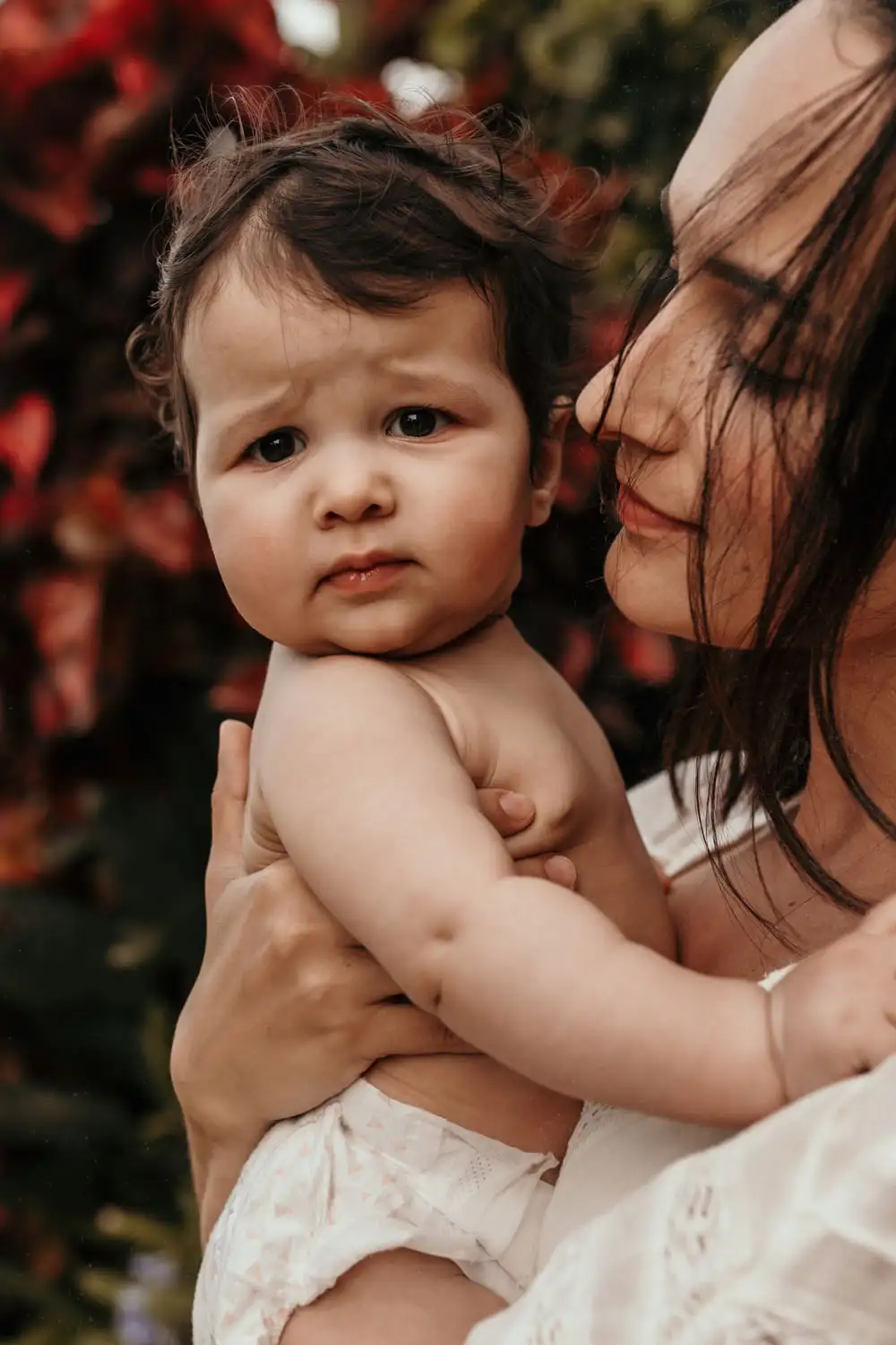 Mother looking at baby. Baby looking at camera
